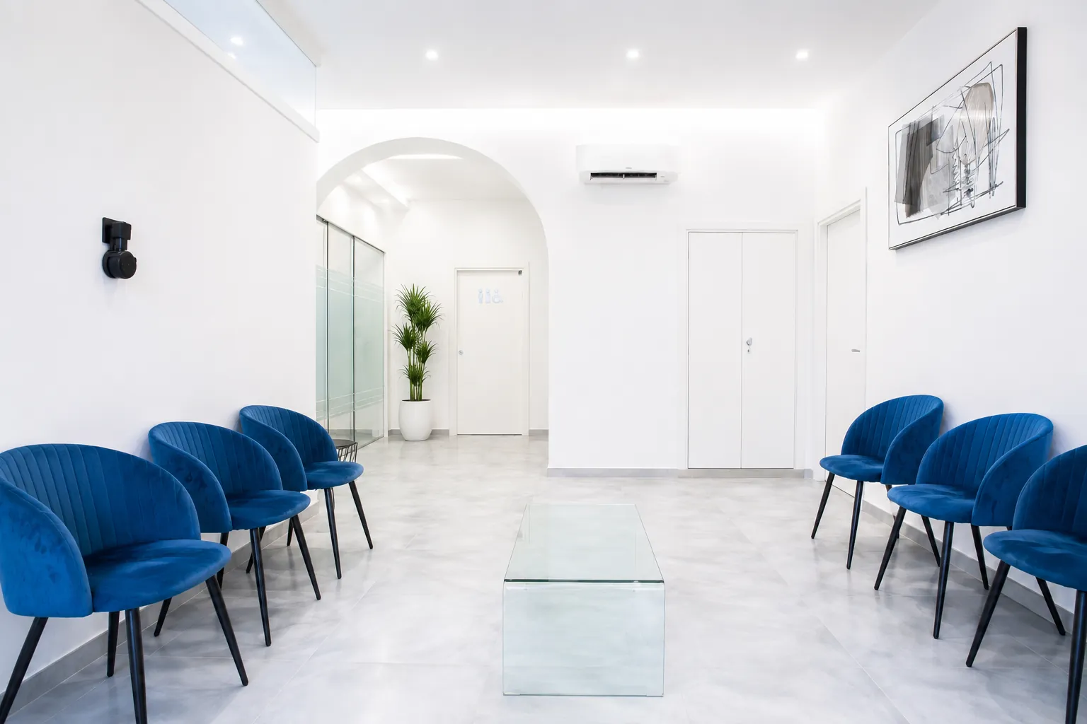 Sala d’attesa dello studio, con poltroncine blu sui due lati e arco centrale